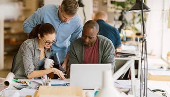 group of three people around a desk